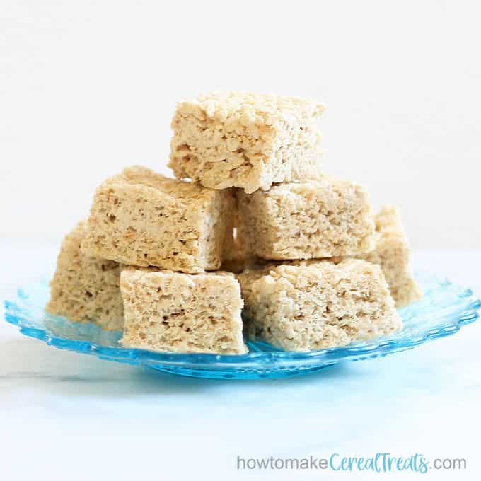 front view of brown butter Rice krispie treats stacked with title brown butter Rice krispie treats stacked with title brown butter Rice krispie treats stacked with title brown butter Rice krispie treats on blue glass plate 