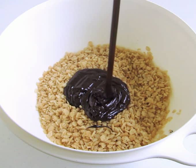 hälla en blandning av smält smör, marshmallows, chokladflis och kakaopulver i en skål fylld med Rice Krispies spannmål
