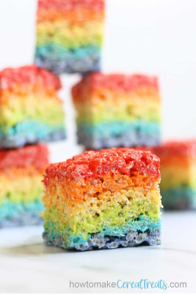 close up of rainbow rice krispie treats with stack in background
