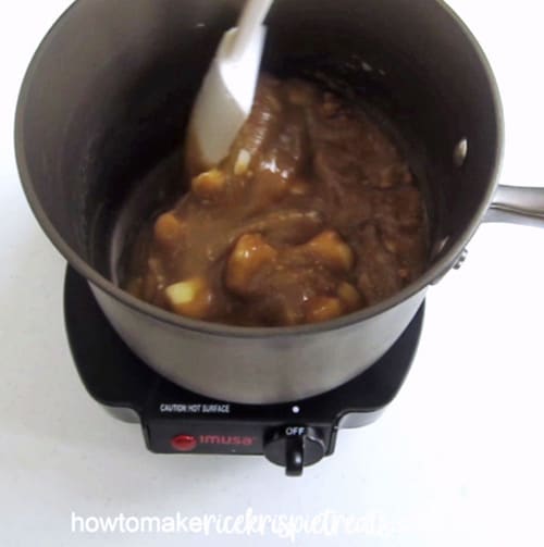 Making homemade caramel in a medium saucepan to create Caramel Rice Krispie Treats.