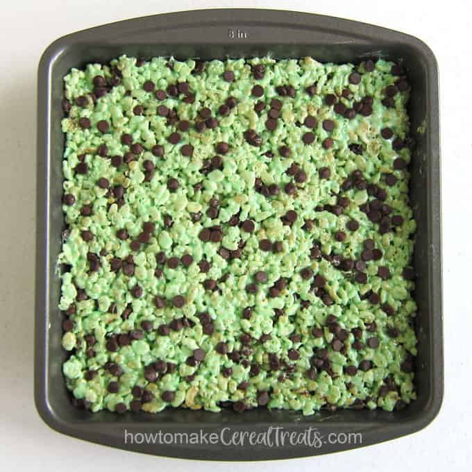 8-inch square pan filled with mint chocolate chip marshmallow cereal treats topped with mini chocolate chips