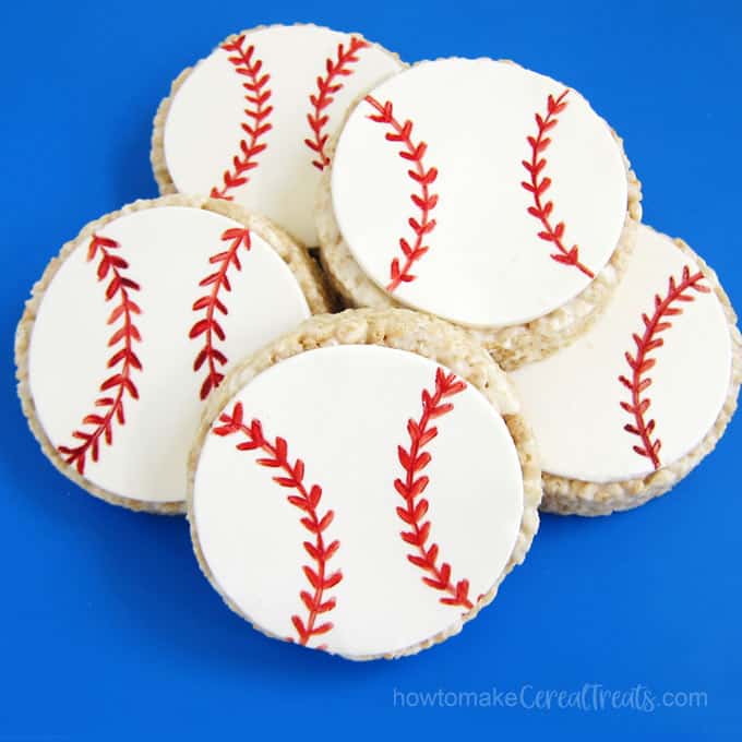 Round rice krispie treat baseballs stacked on top of each other on a blue mat. 