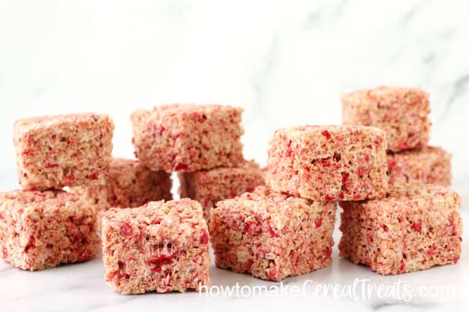 strawberry speckled rice crispy treats stacked up on a marble slab