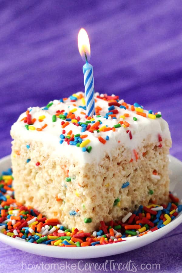 birthday cake rice krispie treats topped with vanilla frosting, rainbow sprinkles and a birthday candle