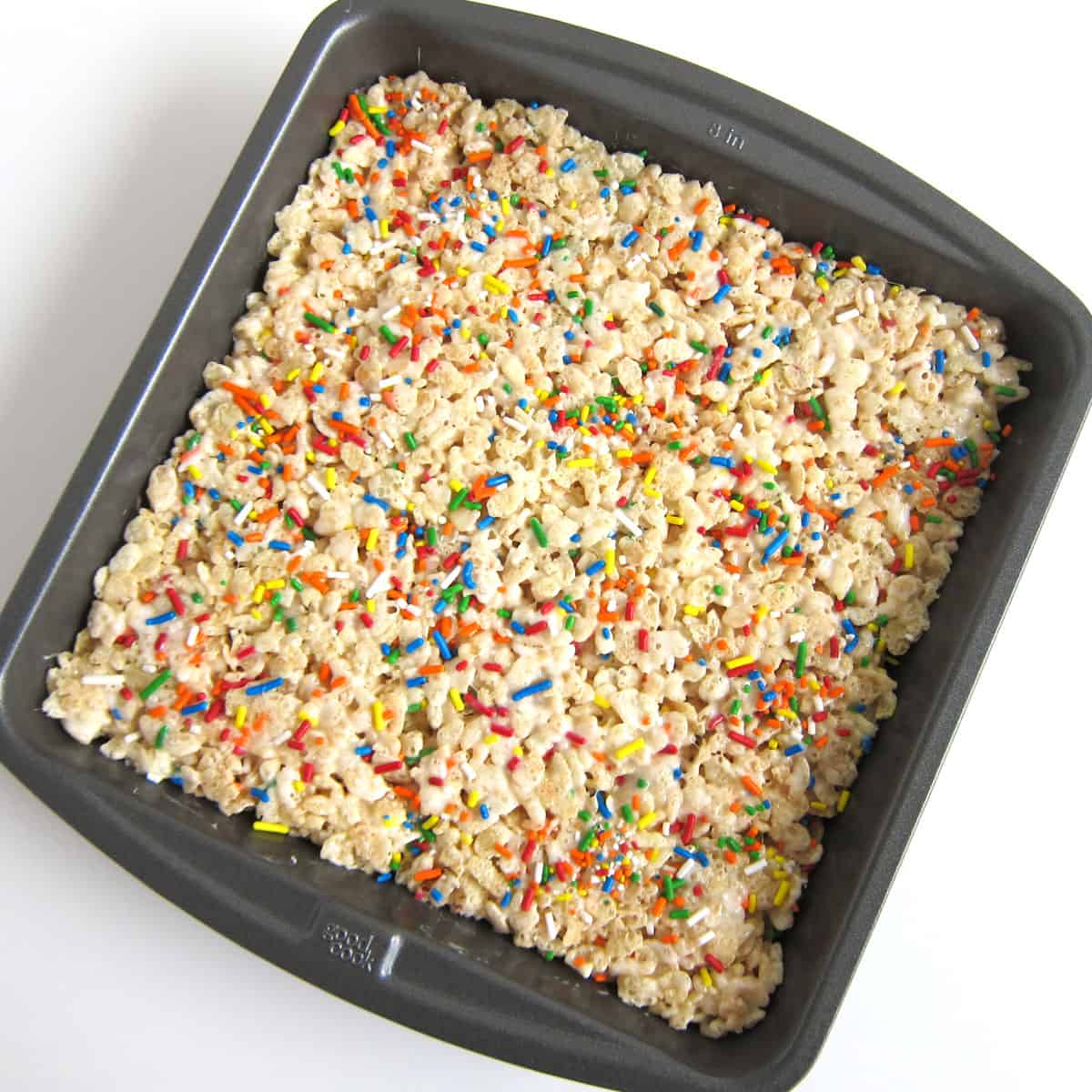 8-inch square pan filled with rainbow sprinkle rice crispy treats