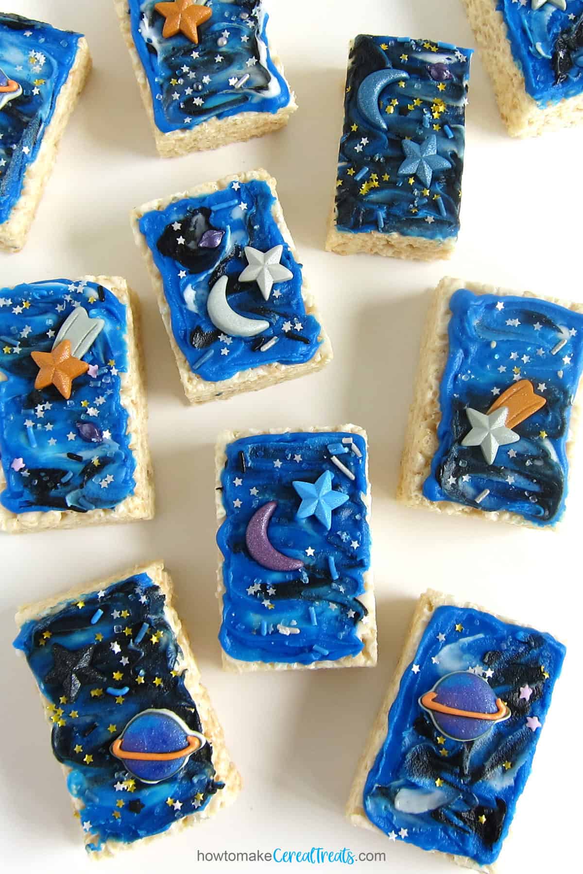 Galaxy Rice Krispie Treats topped with frosting, sprinkles, glitter stars, and icing decorations