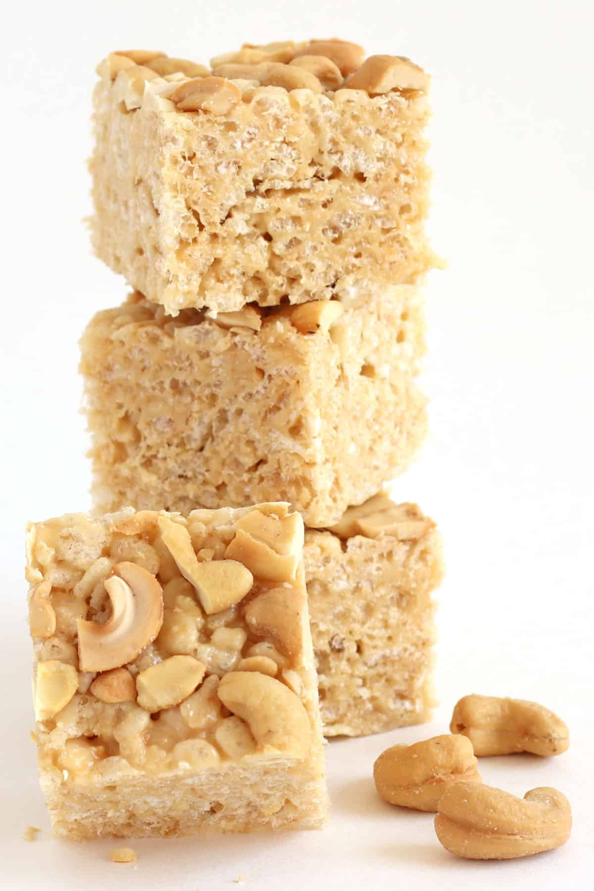 cashew butter rice krispie treats stacked next to roasted and salted cashews