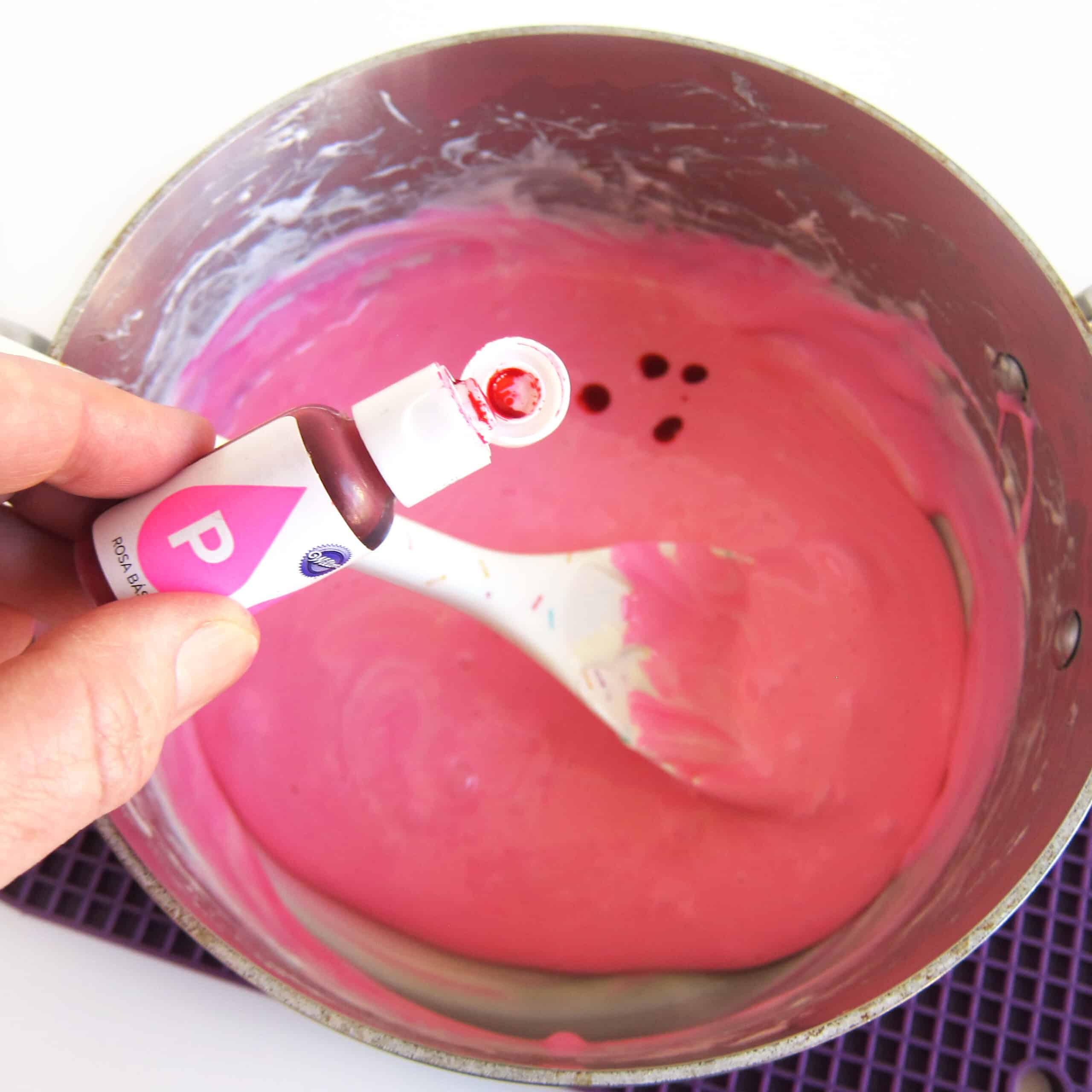 adding more pink food coloring to pink-colored melted marshmallows