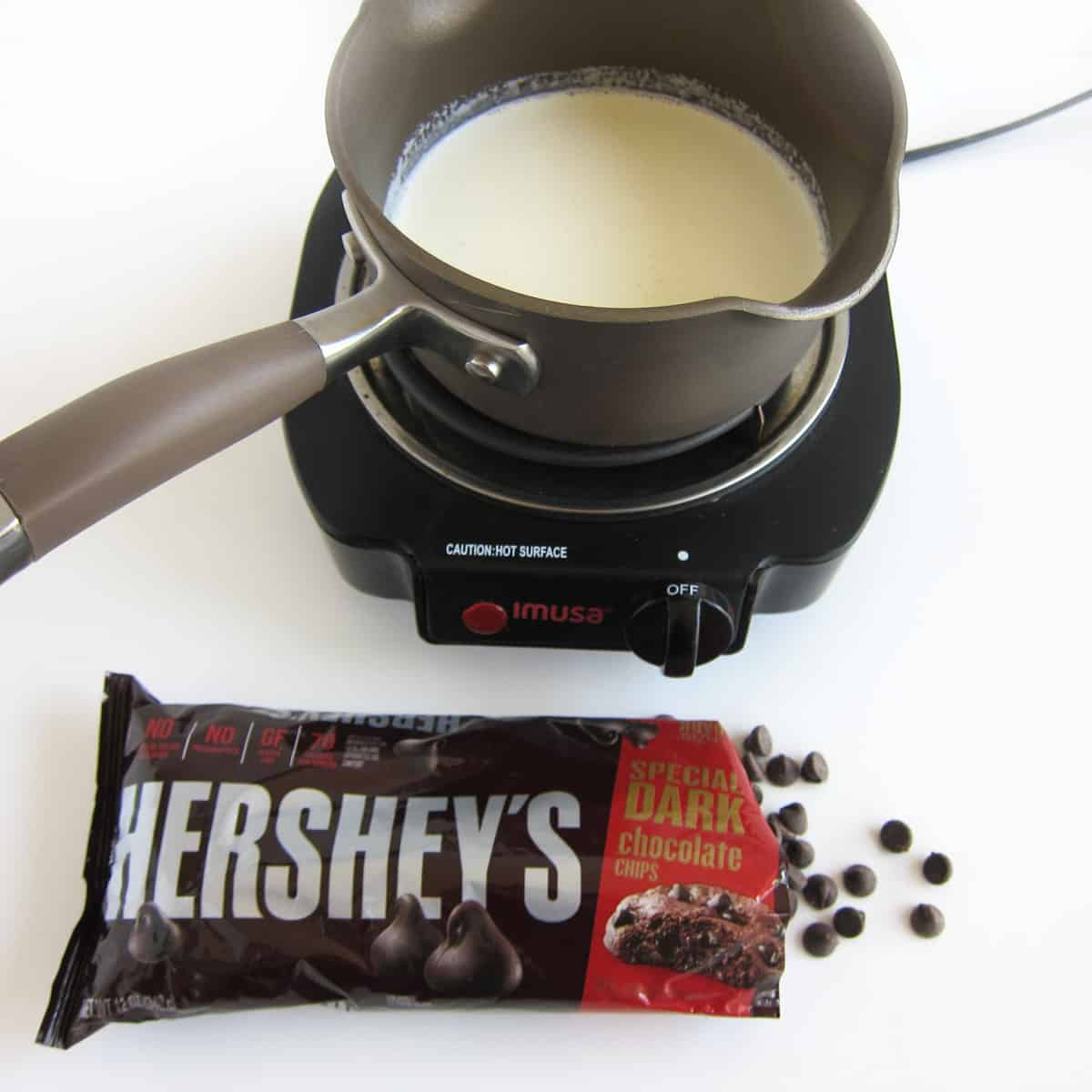 bag of Hershey's Special Dark Chocolate chips in front of a saucepan of heavy cream
