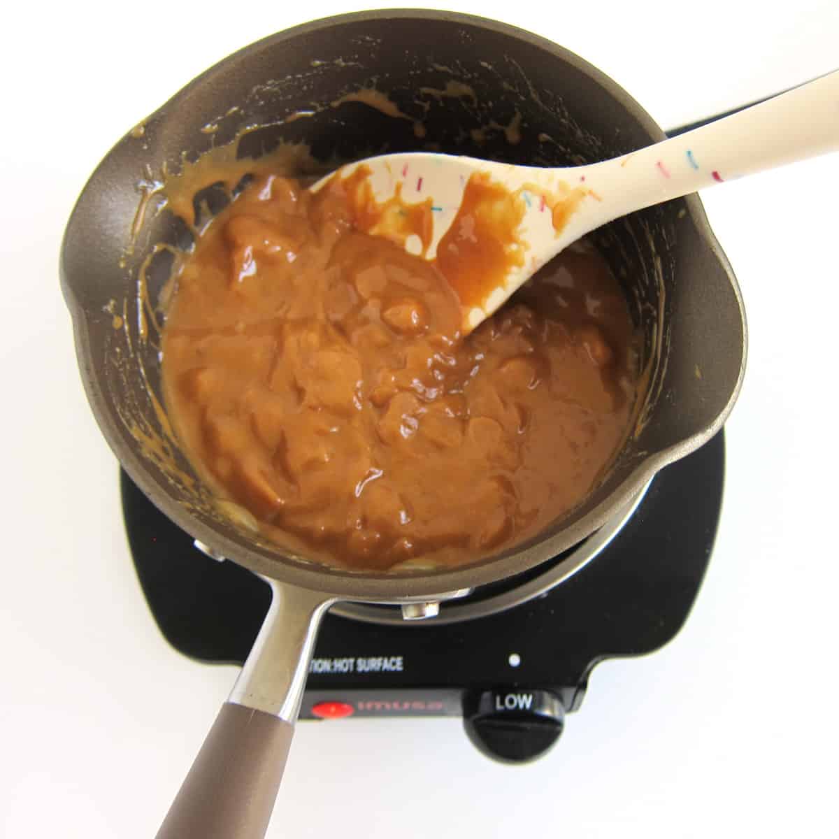 caramel bits and heavy whipping cream melting in saucepan