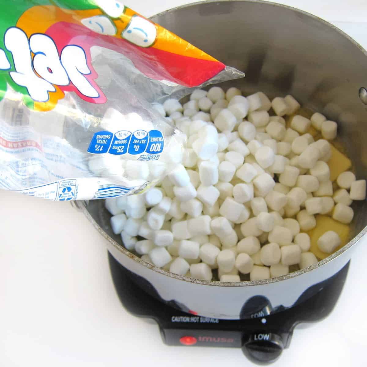 Pouring mini marshmallows into the saucepan with the melting butter
