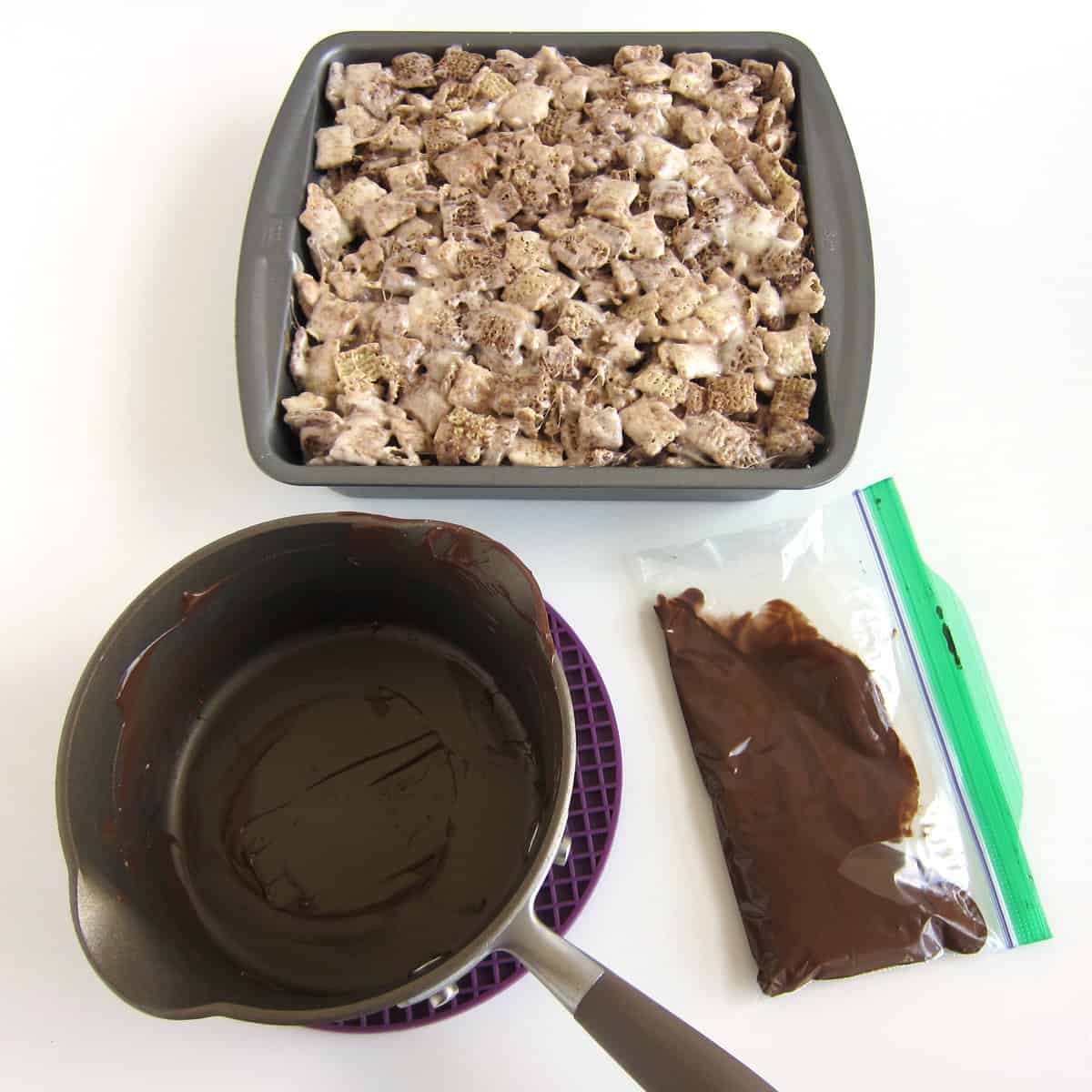 melted chocolate and Nutella in a small zip-top bag next to the empty pan and the pan of Chocolate Chex Bars