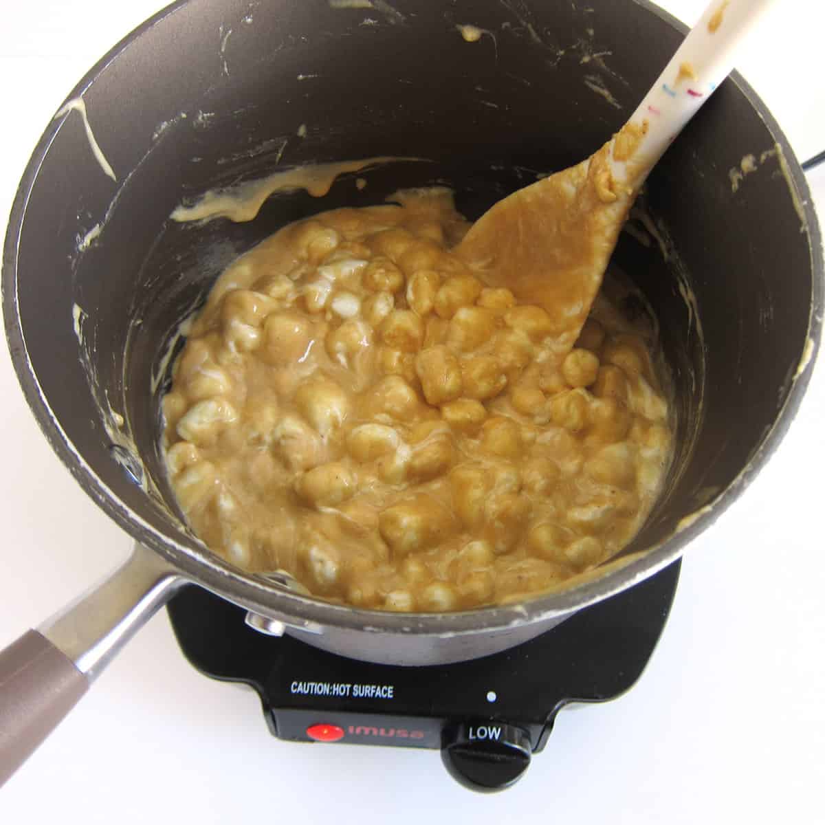 melting marshmallows, butter, and peanut butter over low heat in a saucepan