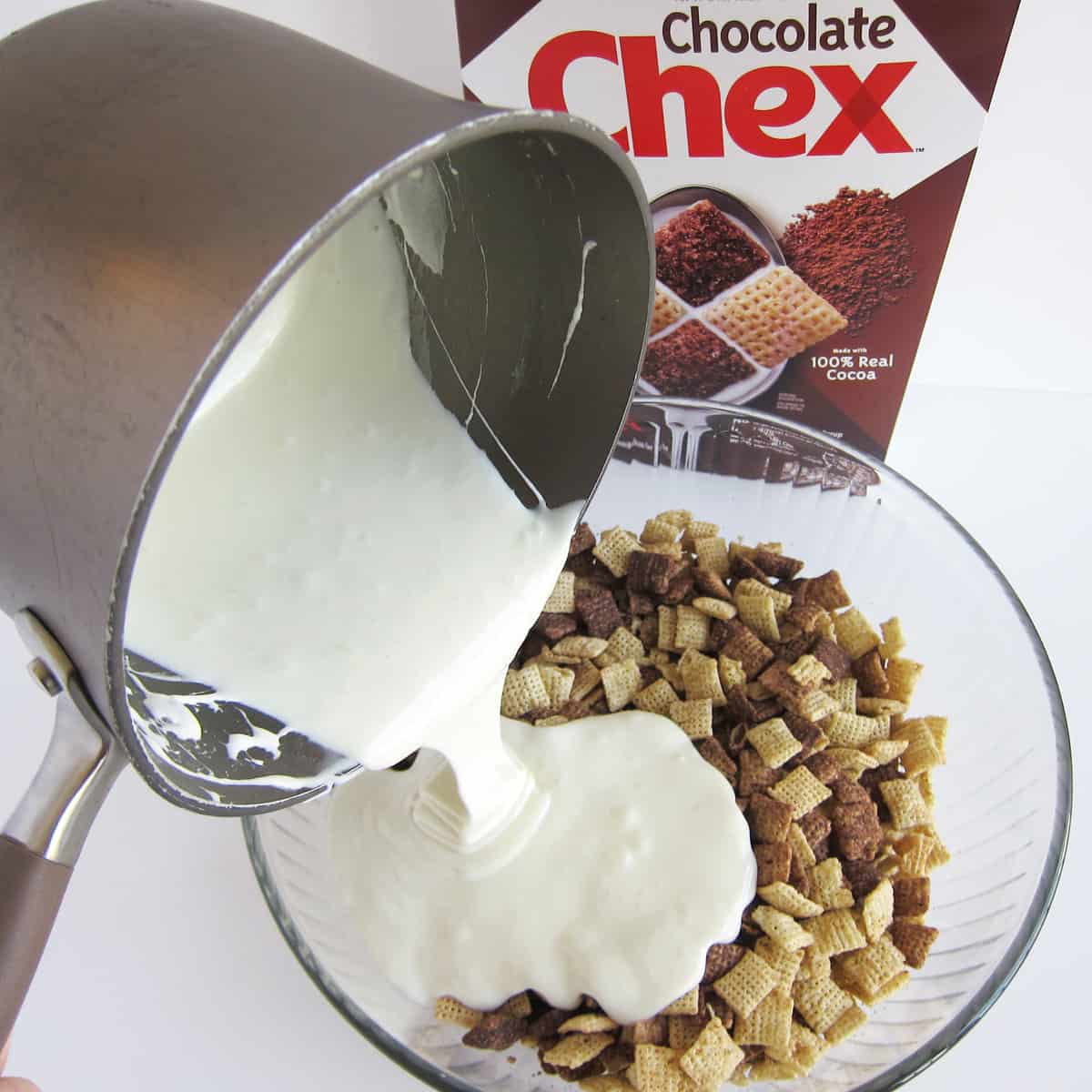 Pouring melted marshmallows and butter over Chocolate Chex cereal in a bowl.