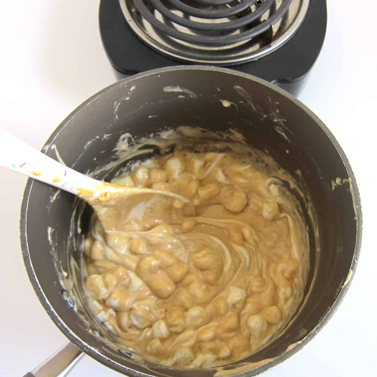 Stirring the melted marshmallows, peanut butter, and butter.