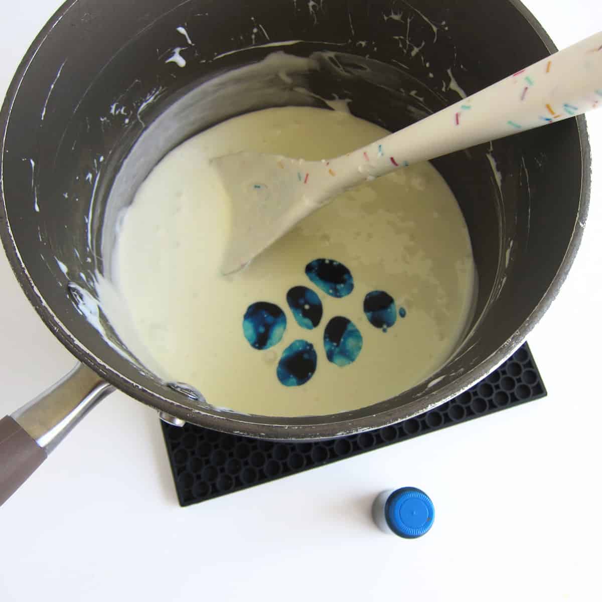 Drops of blue food coloring are added to the pan of melted butter and marshmallows.
