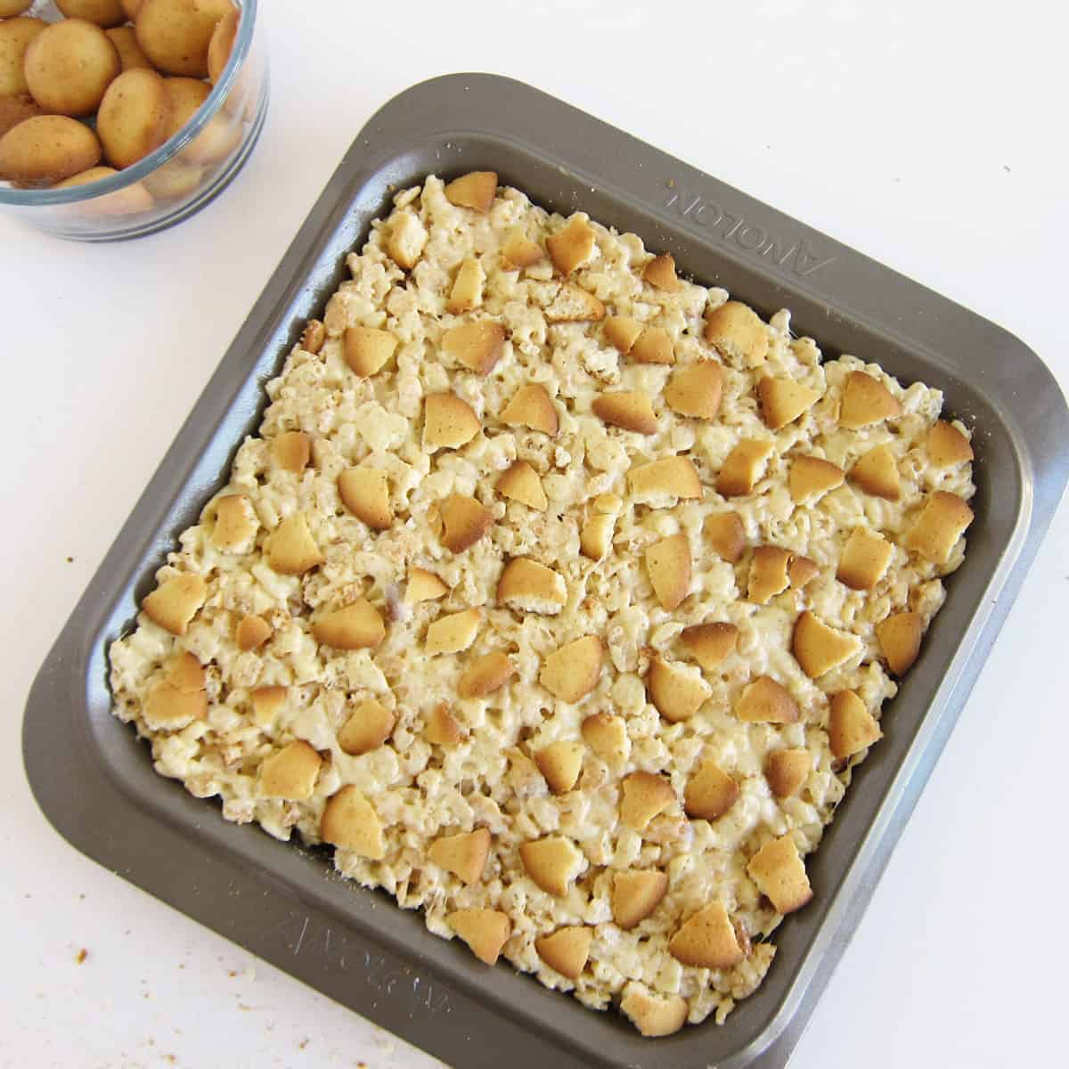 vanilla wafer cookie pieces arranged on top of the banana pudding cereal treats in a pan
