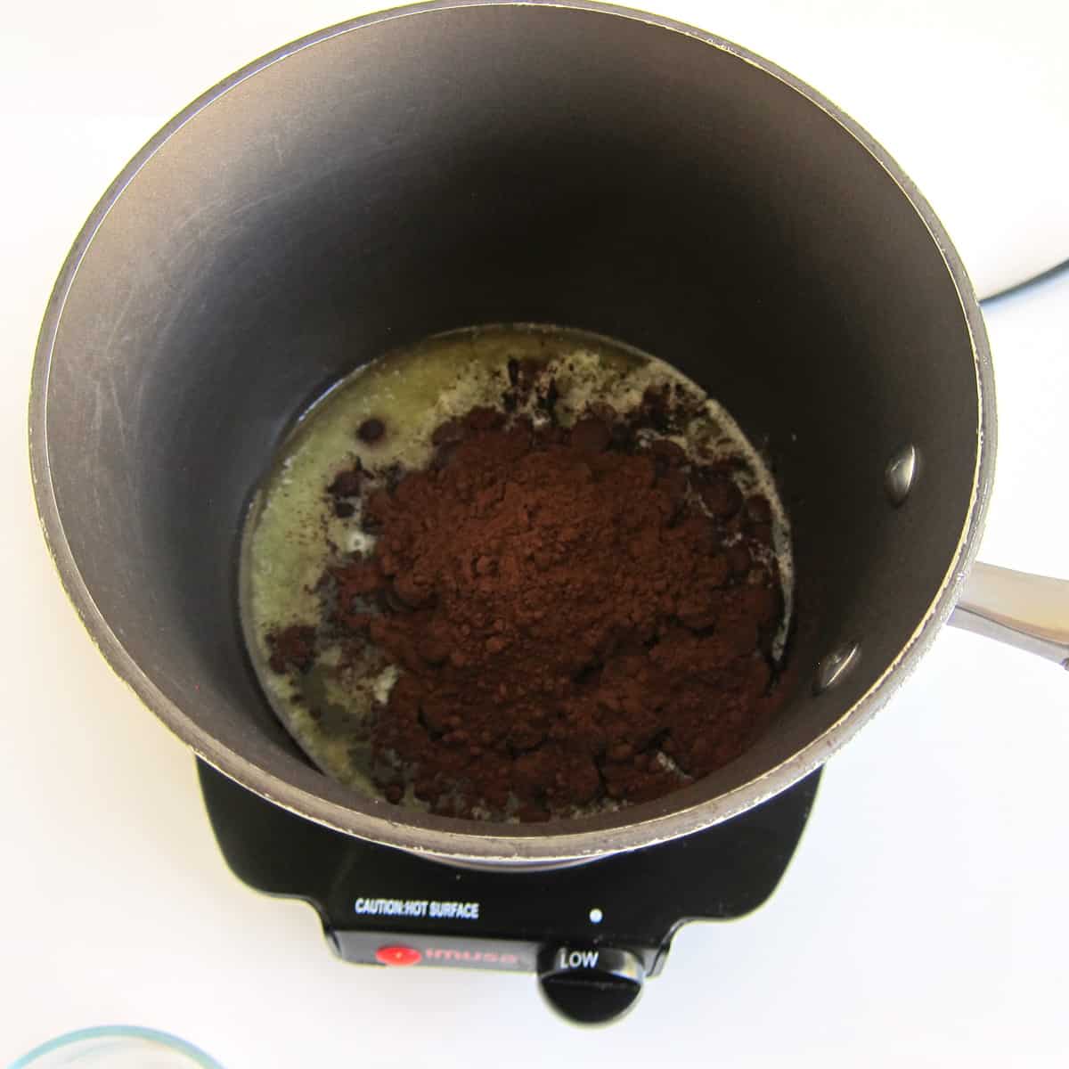 butter, chocolate chips, and cocoa powder melting in a saucepan over low heat
