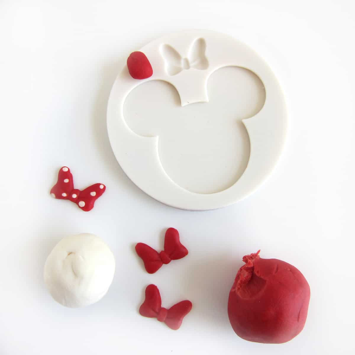 Minnie Mouse silicone mold surrounded by red and white modeling chocolate and bows
