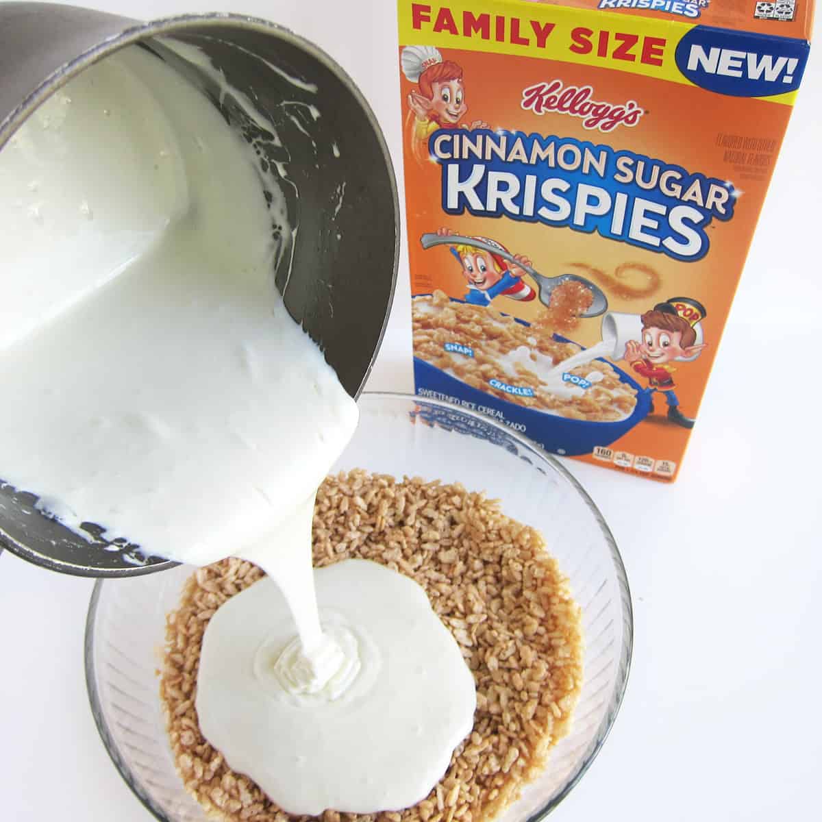 Melted butter and marshmallows being poured over Kellogg's Cinnamon Sugar Krispies in a mixing bowl next to a box of the Rice Krispies cereal.