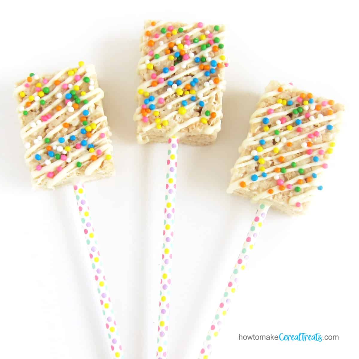 Rice Krispie treat lollipops drizzled with white chocolate and topped with rainbow Crispearls sprinkles.