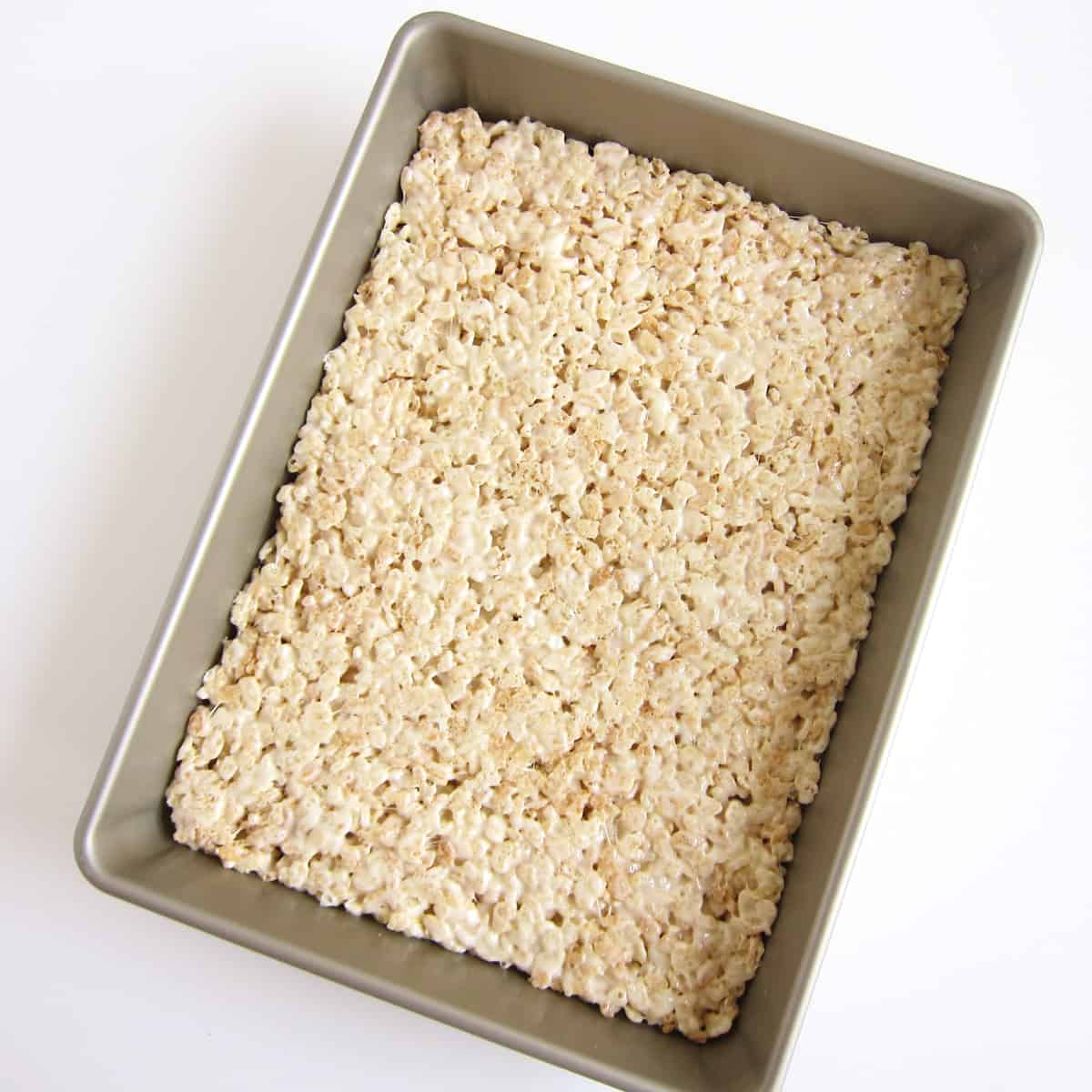White chocolate Rice Krispie Treats spread into a 9x13-inch baking pan.