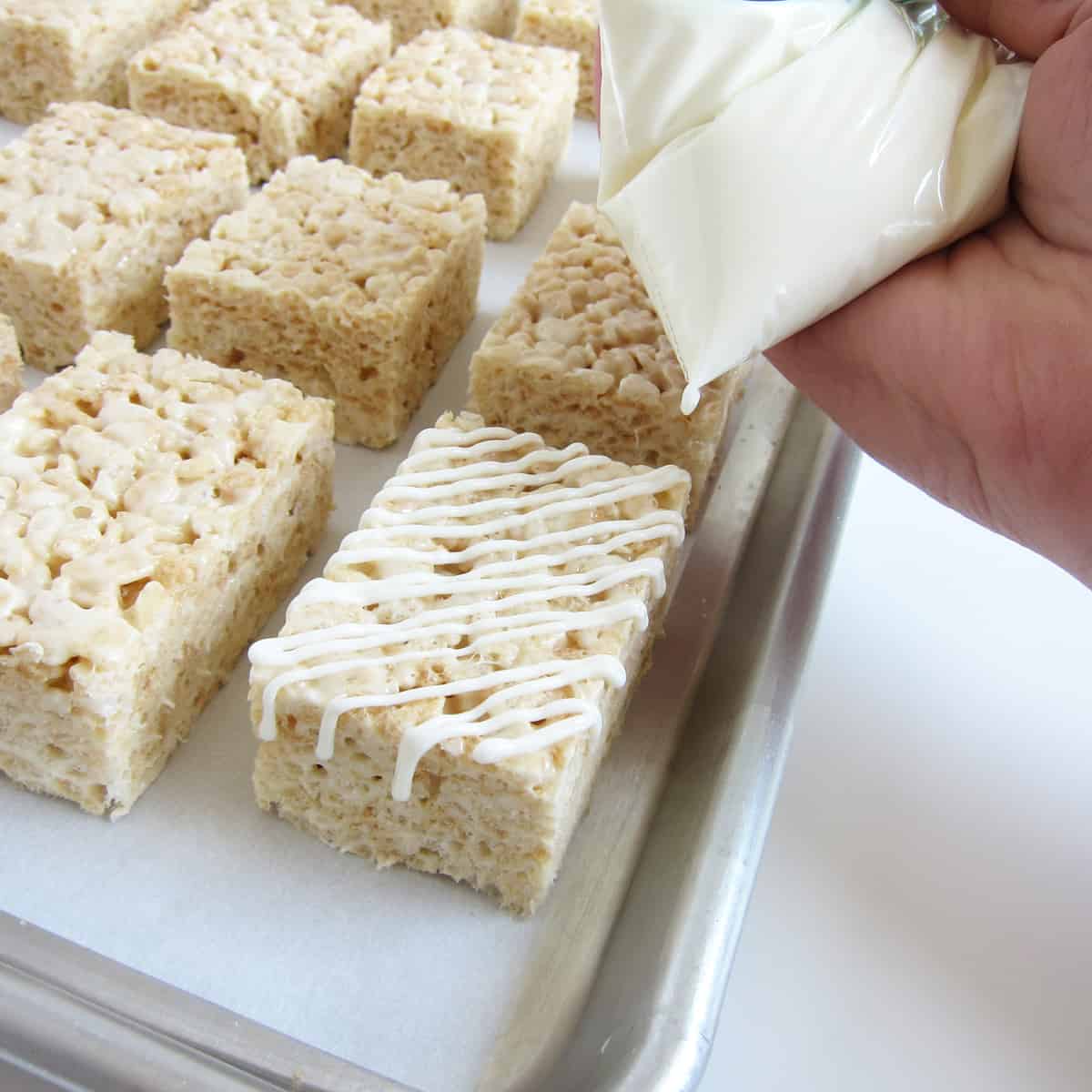 Drizzling white chocolate over a Rice Krispie Treats using a small zip-top bag.