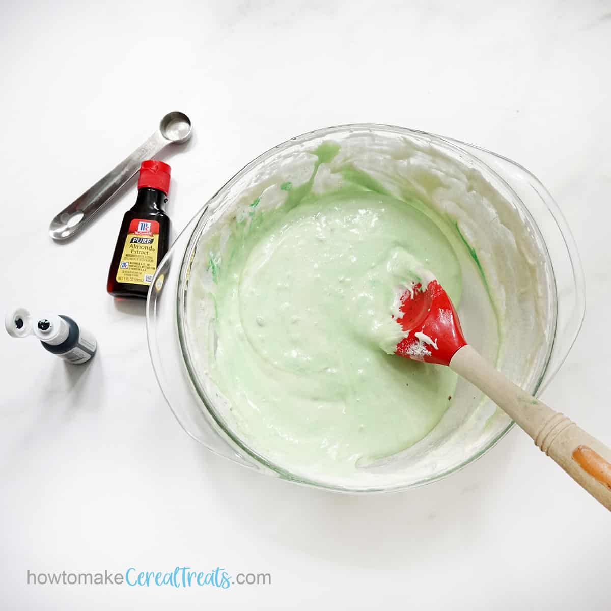 mixing green food coloring into marshmallows, butter, and pistachio pudding mixture