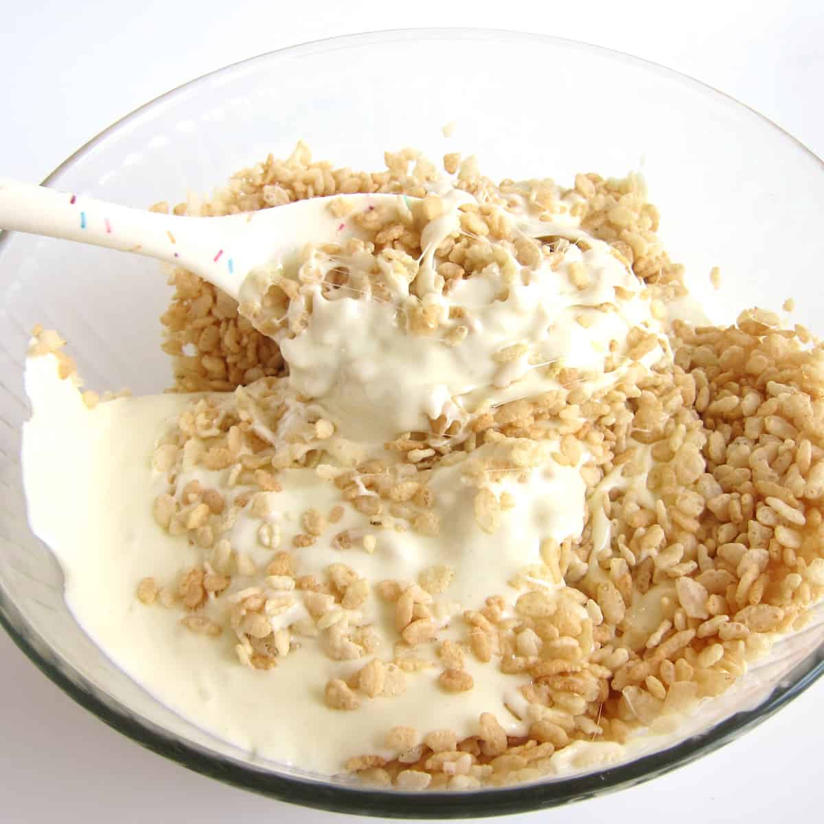Stirring the melted white chocolate marshmallows into the crisp rice cereal.