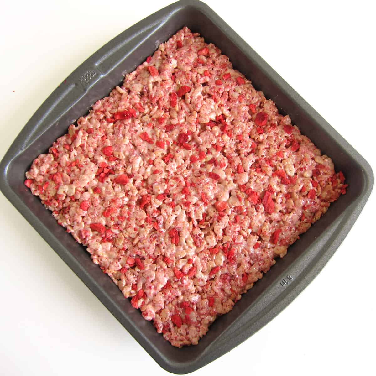 8-inch non-stick pan filled with strawberry crispy treats topped with crushed freeze dried strawberries