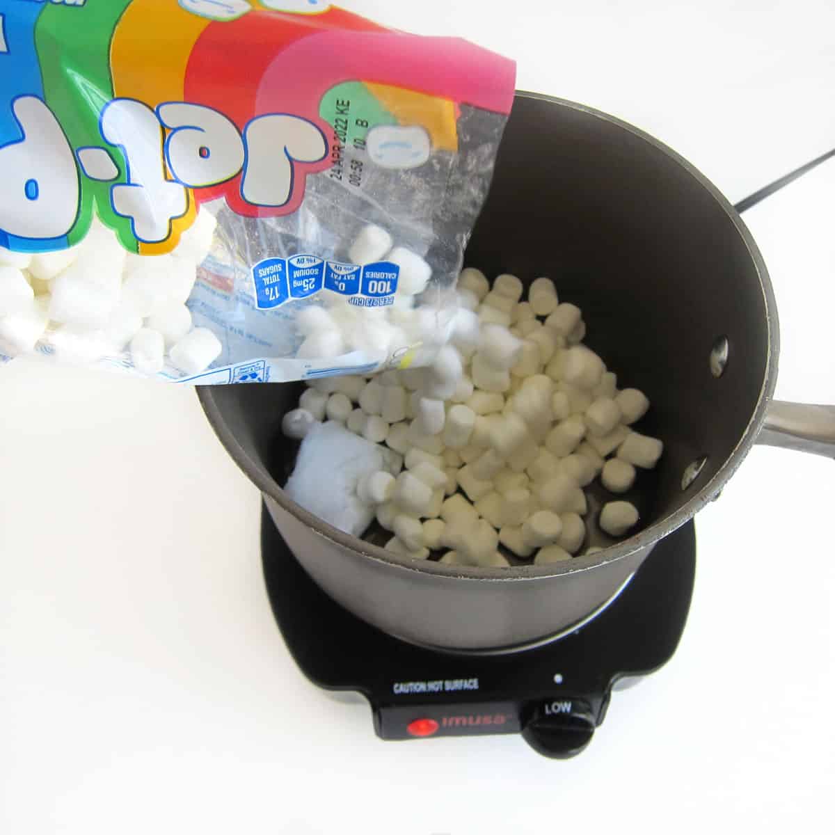 pouring Jet-Puffed Mini Marshmallows over coconut oil in saucepan