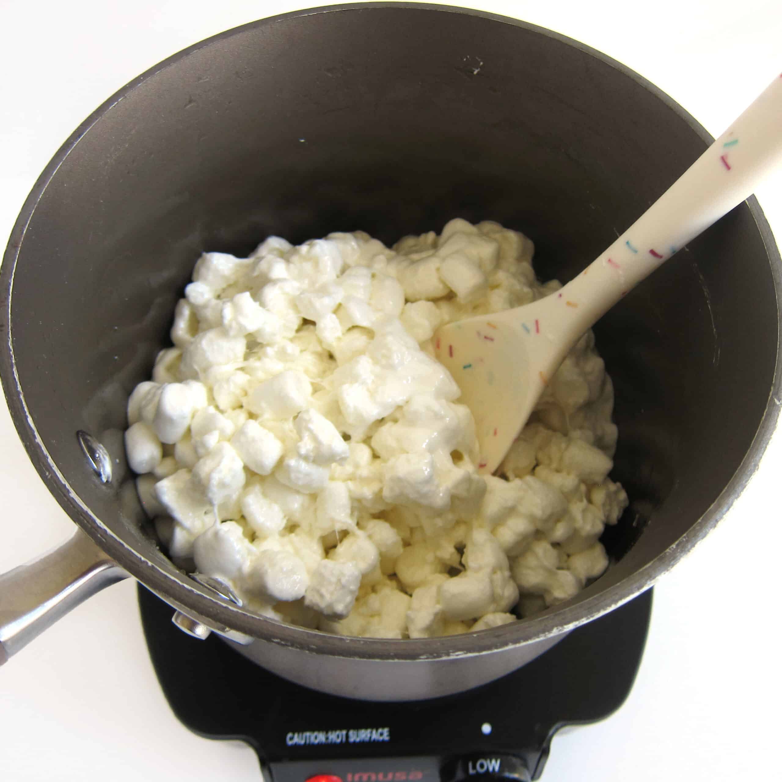 Melting mini marshmallows and coconut oil in a non-stick saucepan.