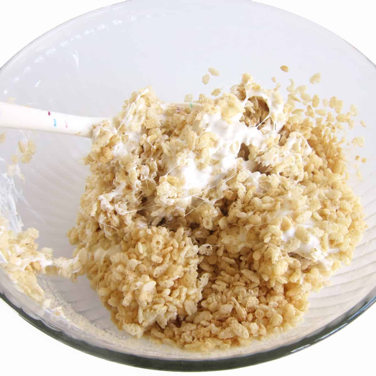 Mixing dairy-free rice krispies treats in a mixing bowl.