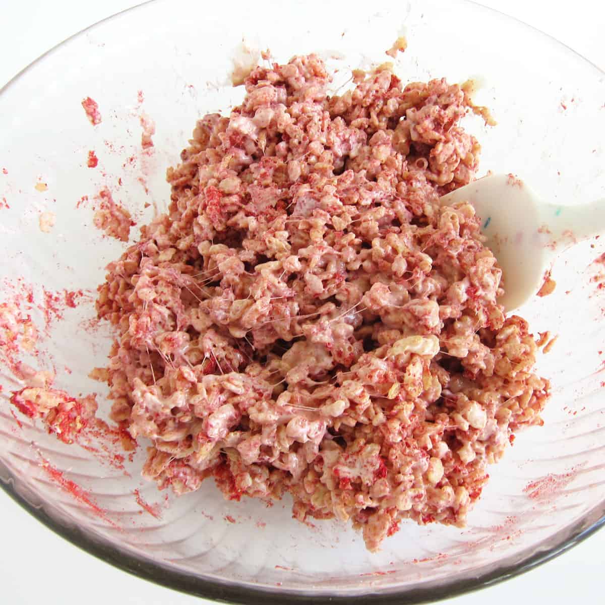 mixing strawberry Rice Krispie treats in a large mixing bowl