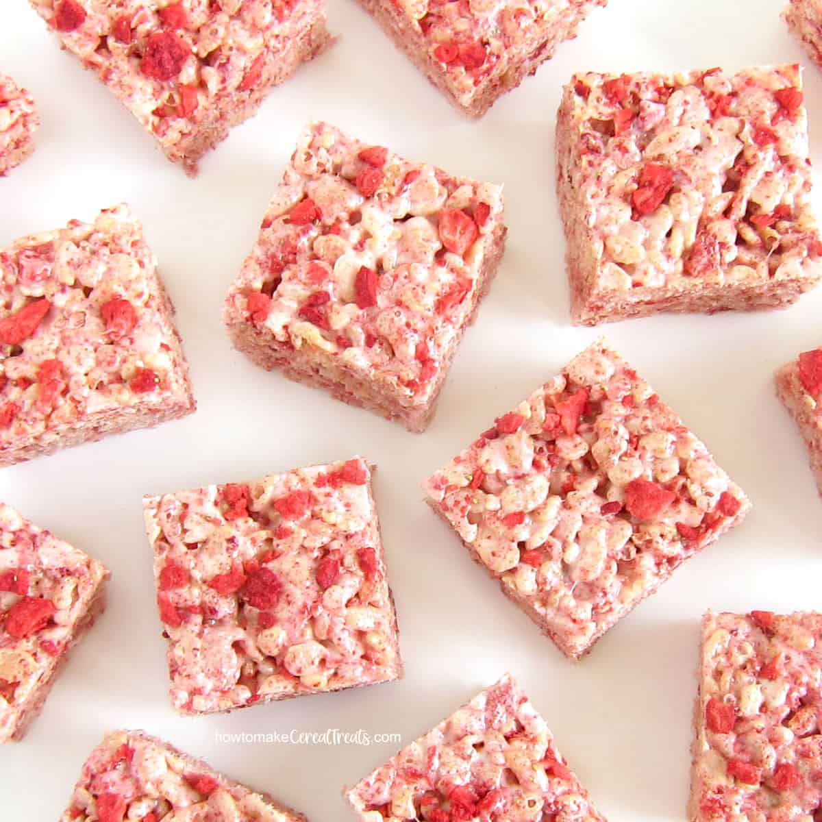 Strawberry-filled rice krispie treat squares arranged on a white background.