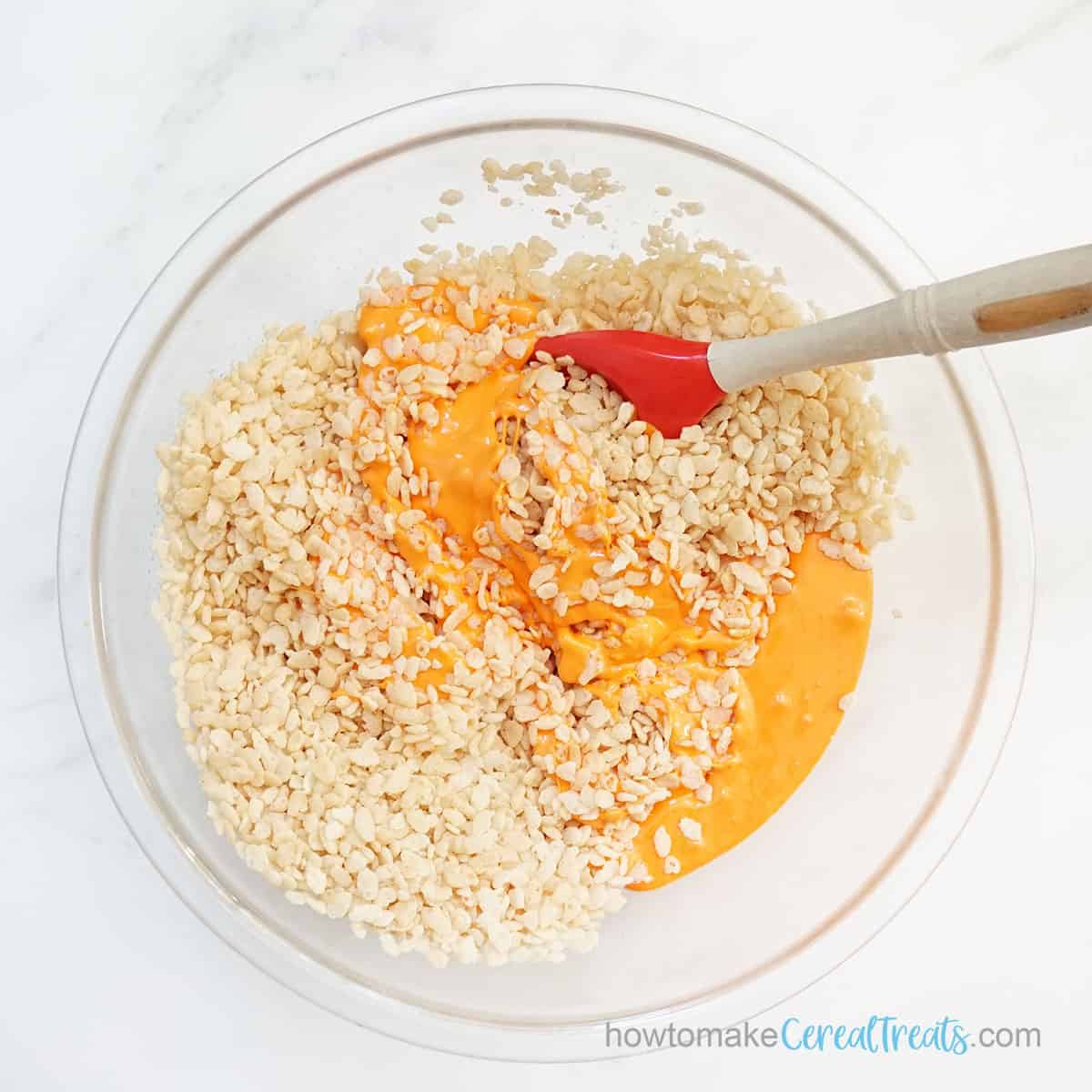 mixing orange Rice Krispie Treats for fall