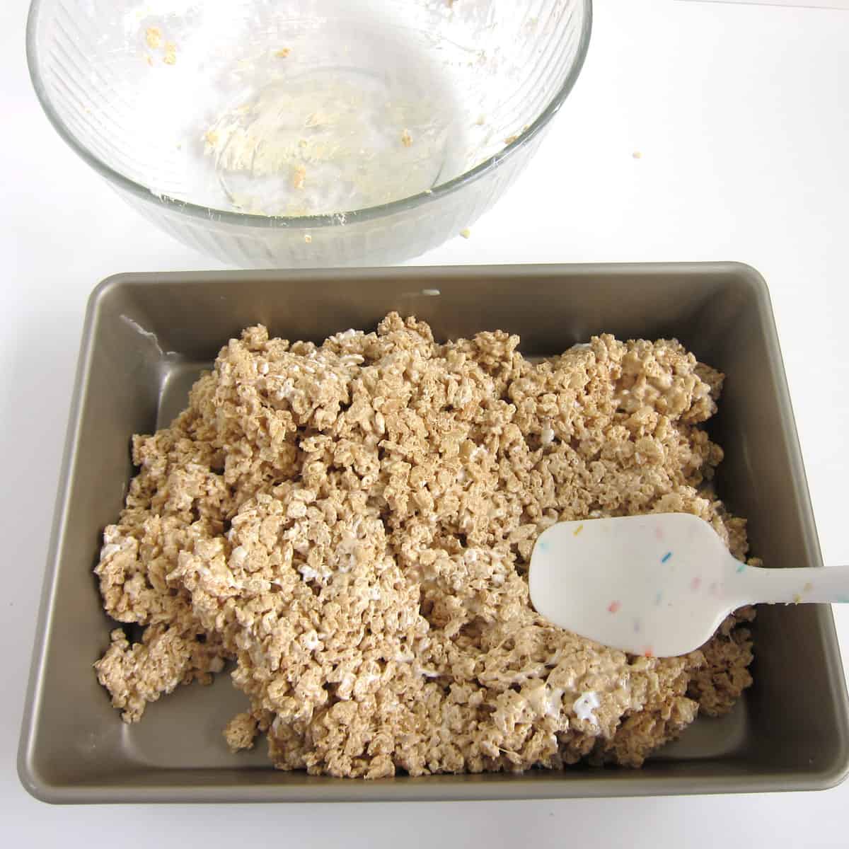spreading the peanut butter marshmallow cereal treat mixture into a greased 9x13-inch pan.