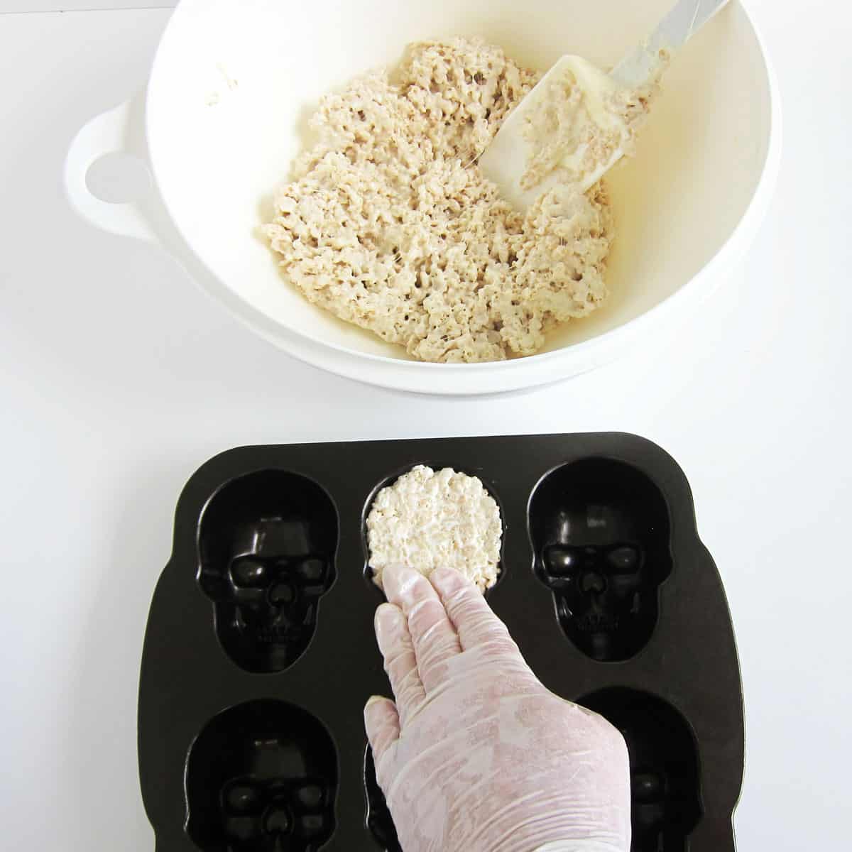 pressing white rice krispie treat mixture into a Nordic Ware skull pan.