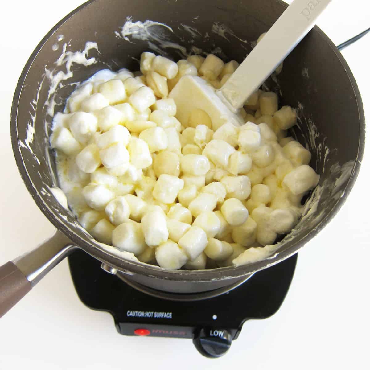 mixing melted butter with mini marshmallows and white candy melts.