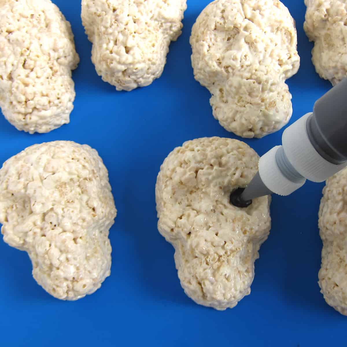 piping black candy melts into the sunken eye cavity in the rice crispy treat skull.