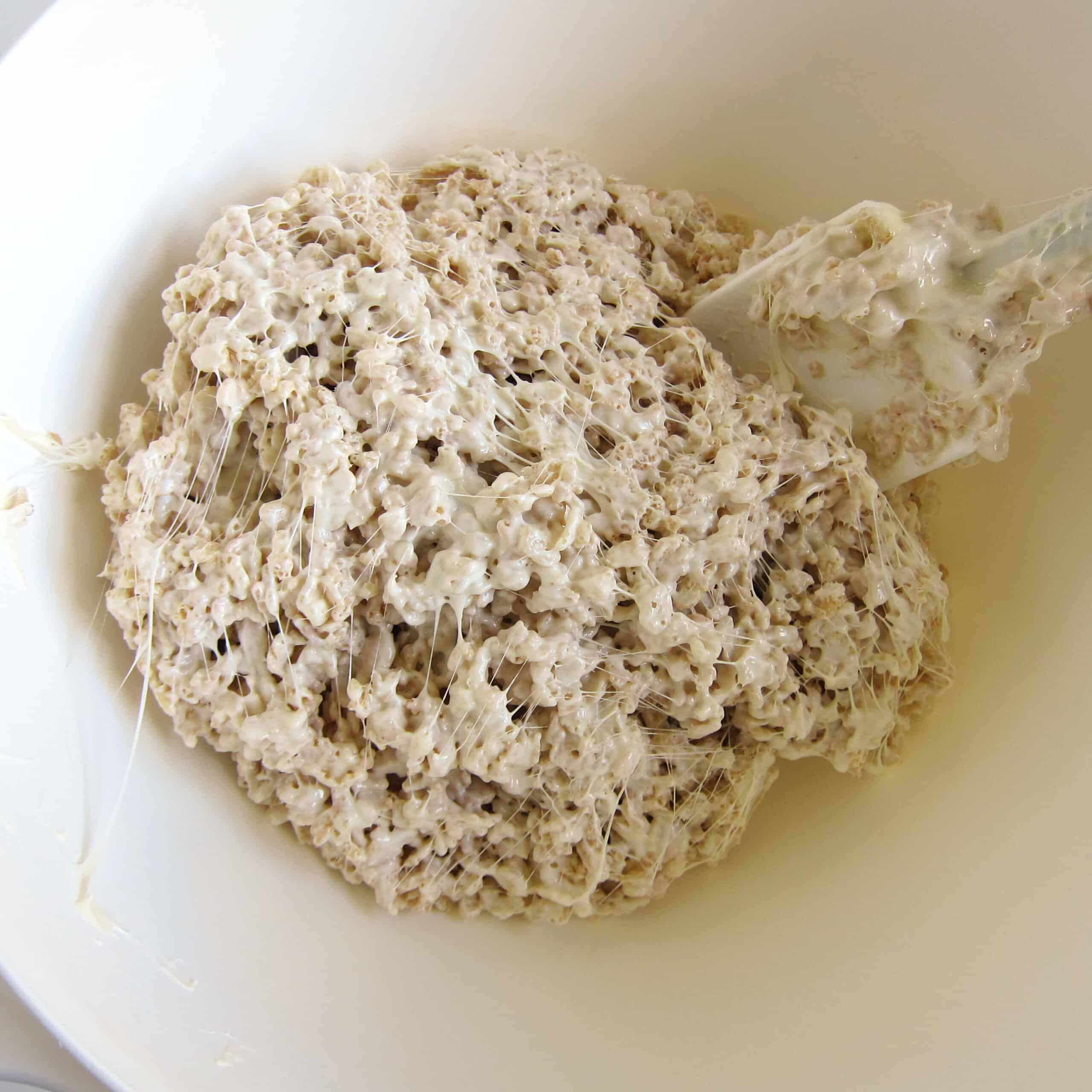 Rice Krispie treat mixture in a white mixing bowl.