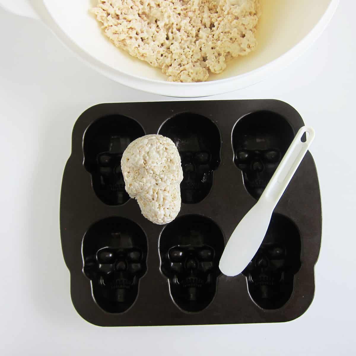 shaped Rice Krispie Treat skull set on the non-stick skull pan along with a plastic blender scraper.
