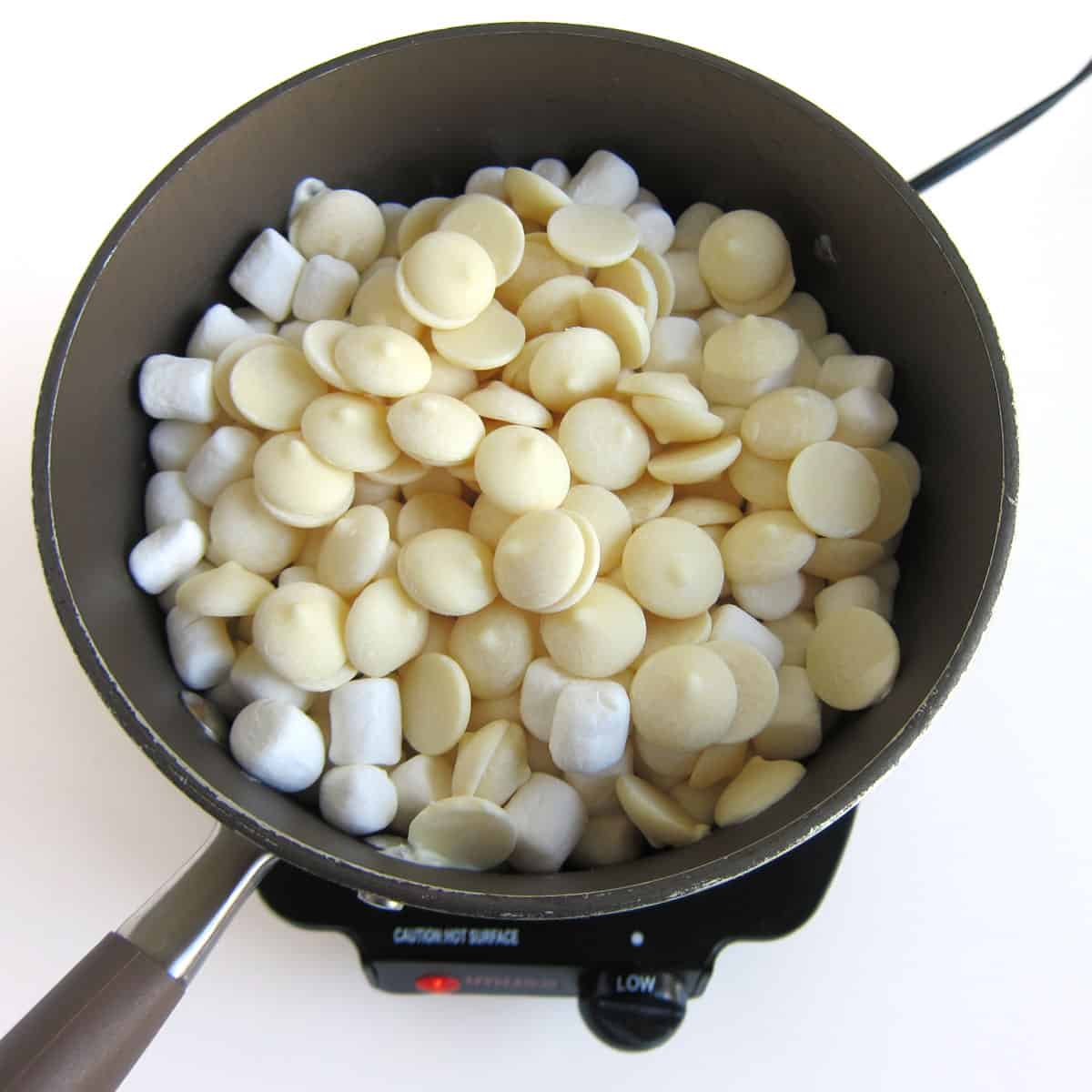 melting butter, marshmallows, and white candy melts in a saucepan.