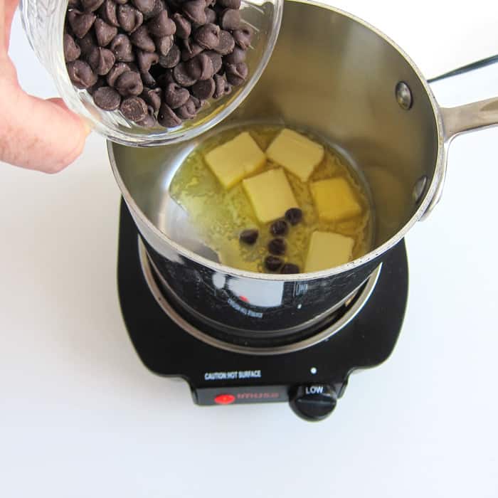 pouring chocolate chips into a pan of melting butter.