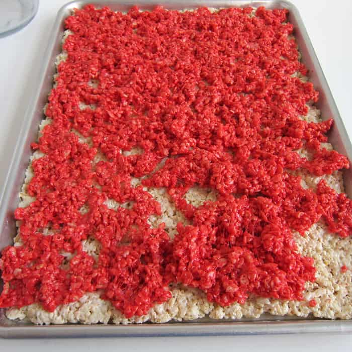 spreading red rice krispie treats over the layer of white rice krispie treats.