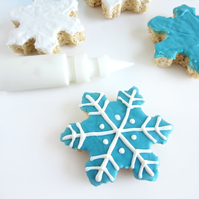 a blue candy-coated Rice Krispie Treat decorated with a white chocolate snowflake.