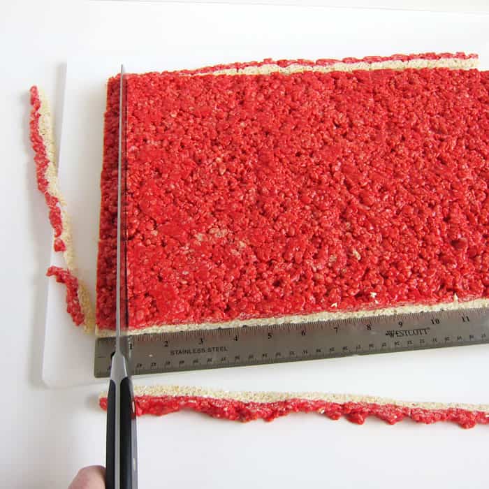 cutting the layered red and white rice krispie treats into ¾-inch wide strips.