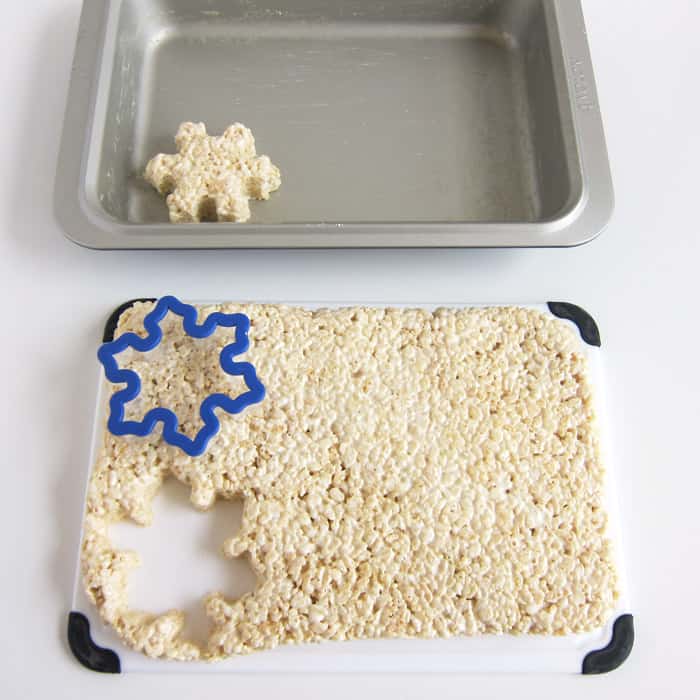 cutting rice krispie treats using a snowflake cookie cutter.