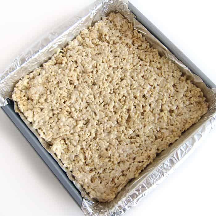 eggnog Rice Krispie Treats spread into an even layer in a tin-foil lined 9-inch square baking pan