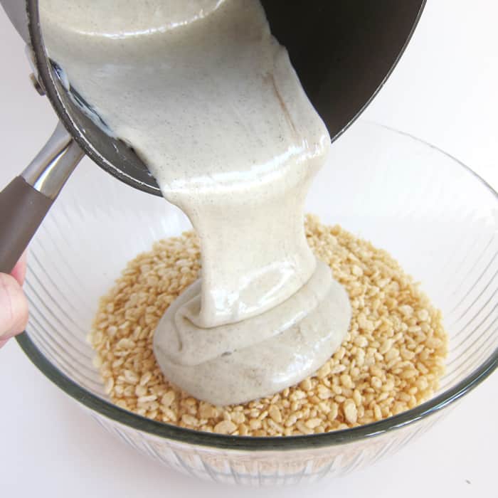 pouring nutmeg-flavored marshmallows over a bowl filled with Rice Krispies cereal.